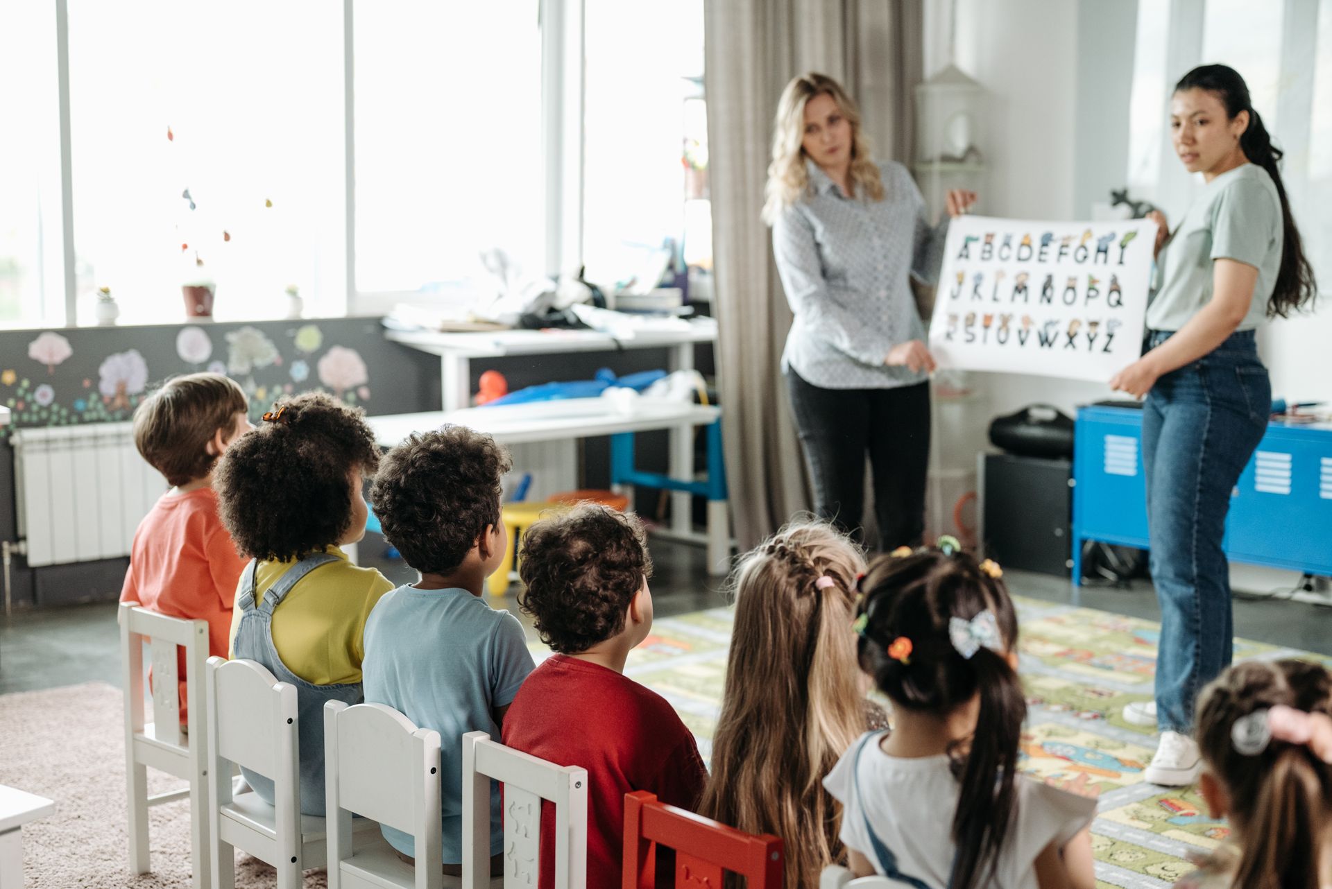 Kinder lernen gemeinsam mit einer pädagogischen Fachkraft in einer Kindergartengruppe